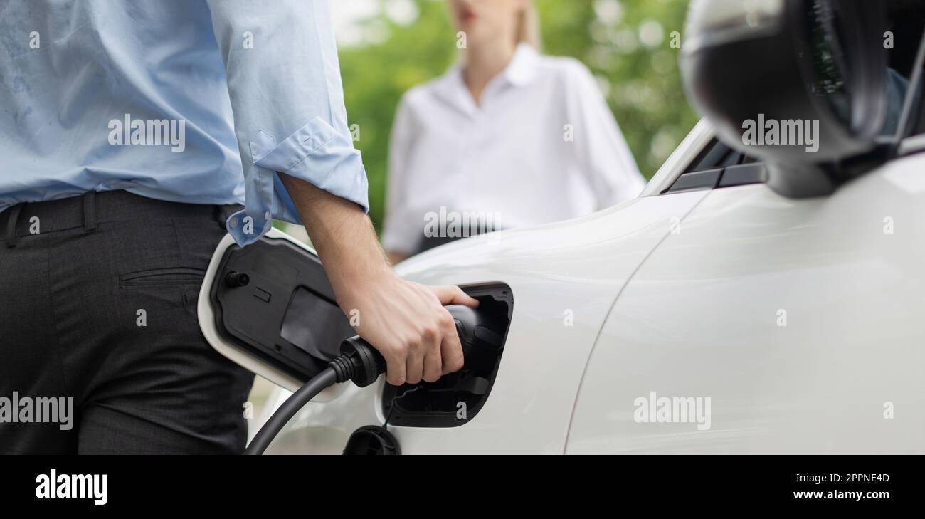 Closeup focus hand insert EV charger to electric vehicle at public