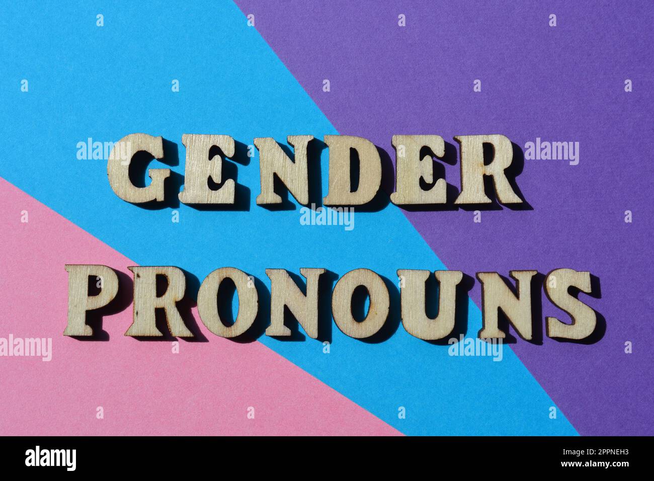 Gender Pronouns, words in wooden alphabet letters isolated on blue, pink and purple background Stock Photo