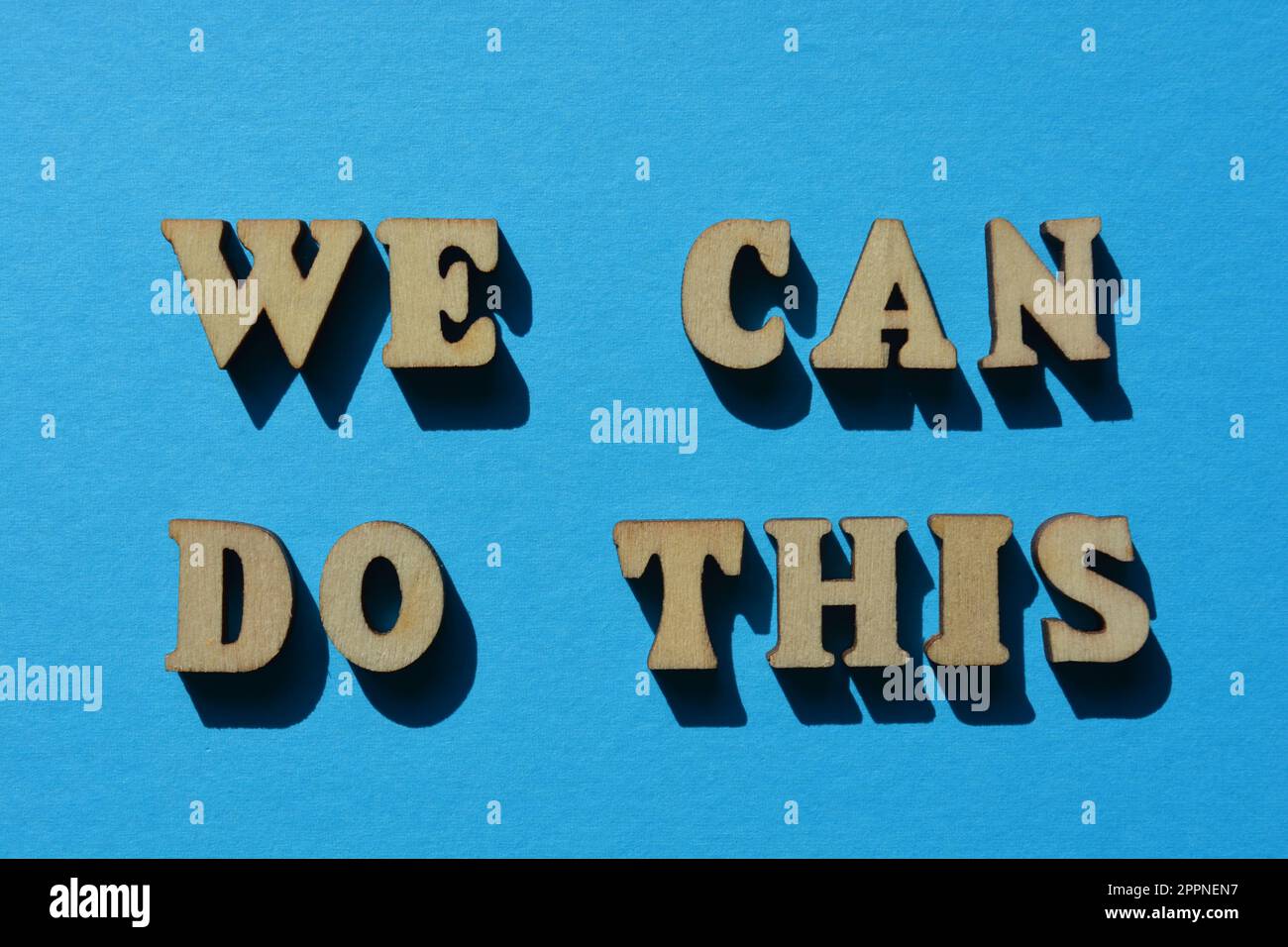We Can Do This, words in wooden alphabet letters isolated on blue background Stock Photo