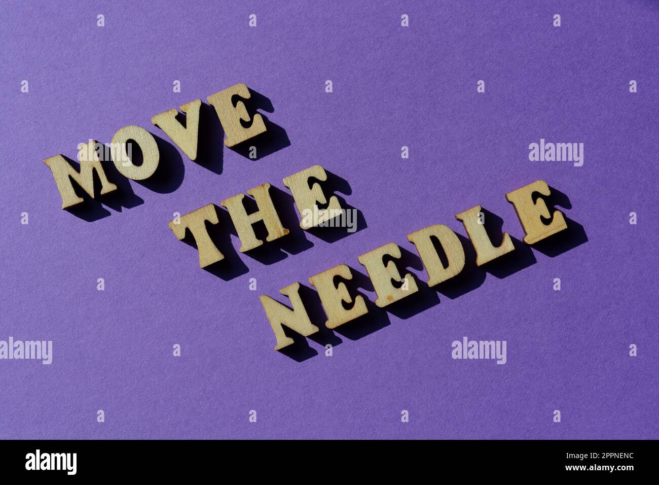 Move The Needle, words in wooden alphabet letters isolated on purple background Stock Photo