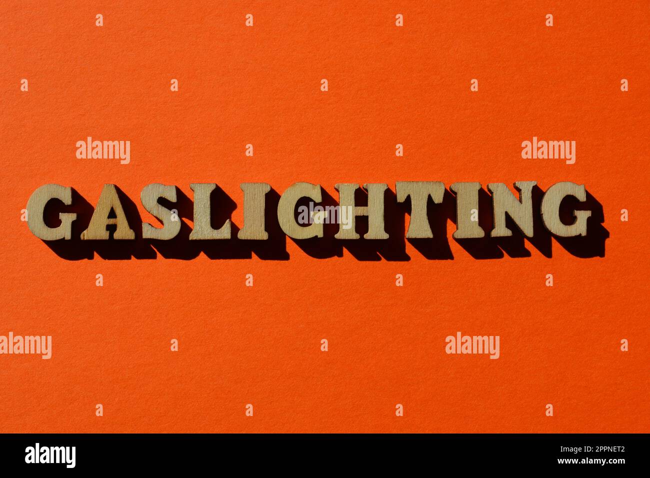 Gaslighting, word in wooden alphabet letters isolated on bright orange background Stock Photo