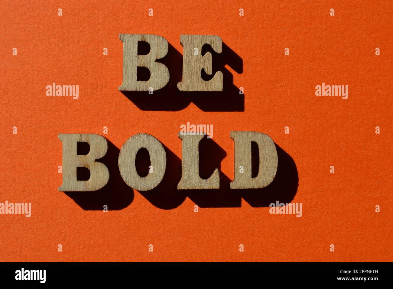 Be Bold, words in wooden alphabet letters isolated on bright orange background Stock Photo