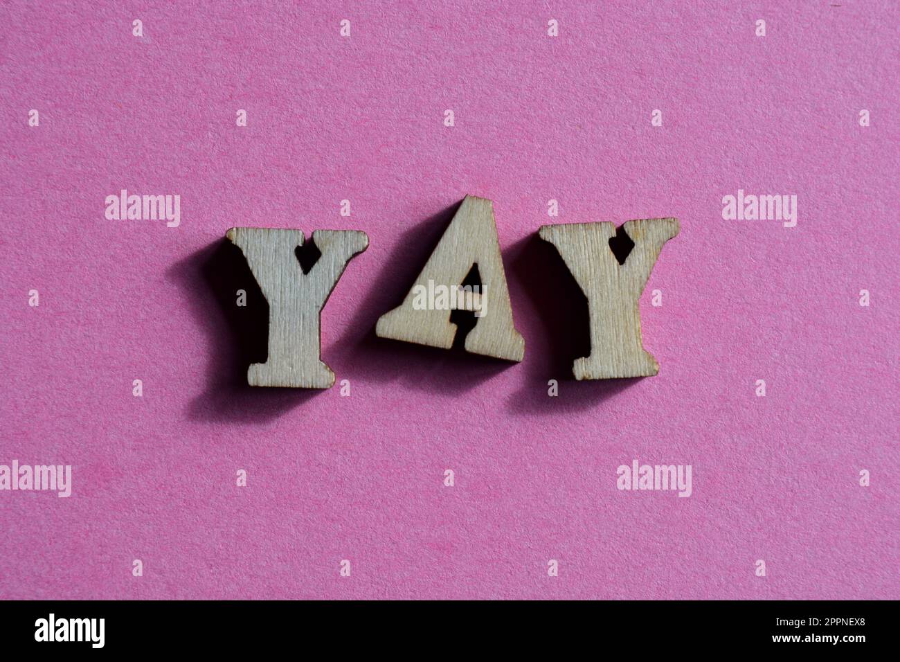 Yay, word in wooden alphabet letters isolated on bright pink background Stock Photo