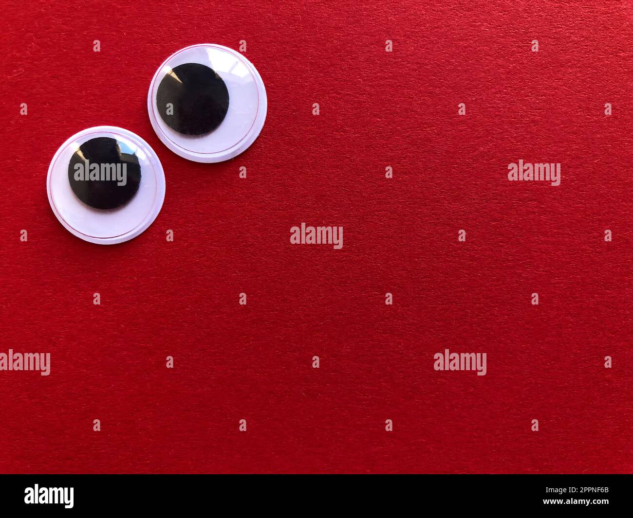 Creative fun background, googly eyes isolated on red background with copy space Stock Photo