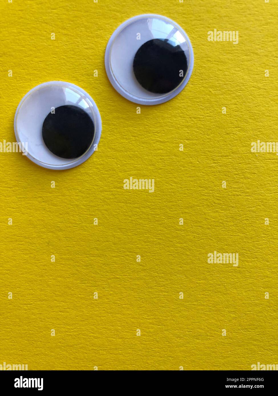 Googly eyes isolated on yellow background with copy space Stock Photo