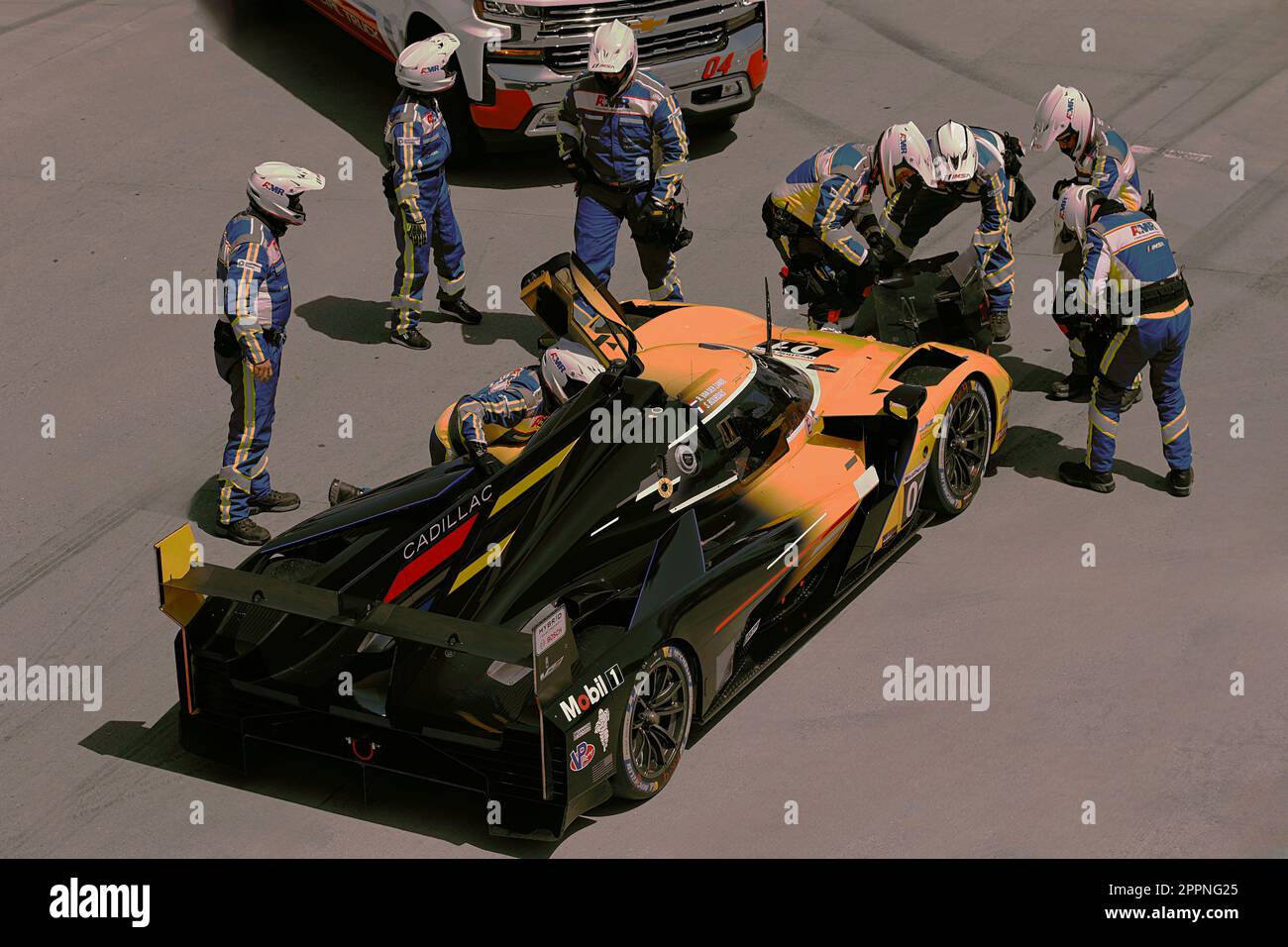 A team of NTT Indy Car Safety crew is gathered around a race car, removing its damaged front spoiler Stock Photo