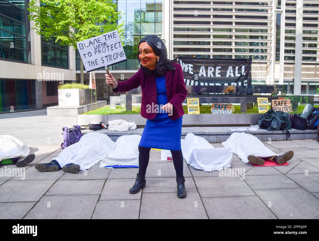 London, UK. 24th April 2023. An activist dressed as Home Secretary Suella Braverman stands next to other activists posing as dead bodies of migrants and people in developing countries affected by climate change outside the Home Office on the fourth and final day of Extinction Rebellion's protests in Westminster. Credit: Vuk Valcic/Alamy Live News Stock Photo