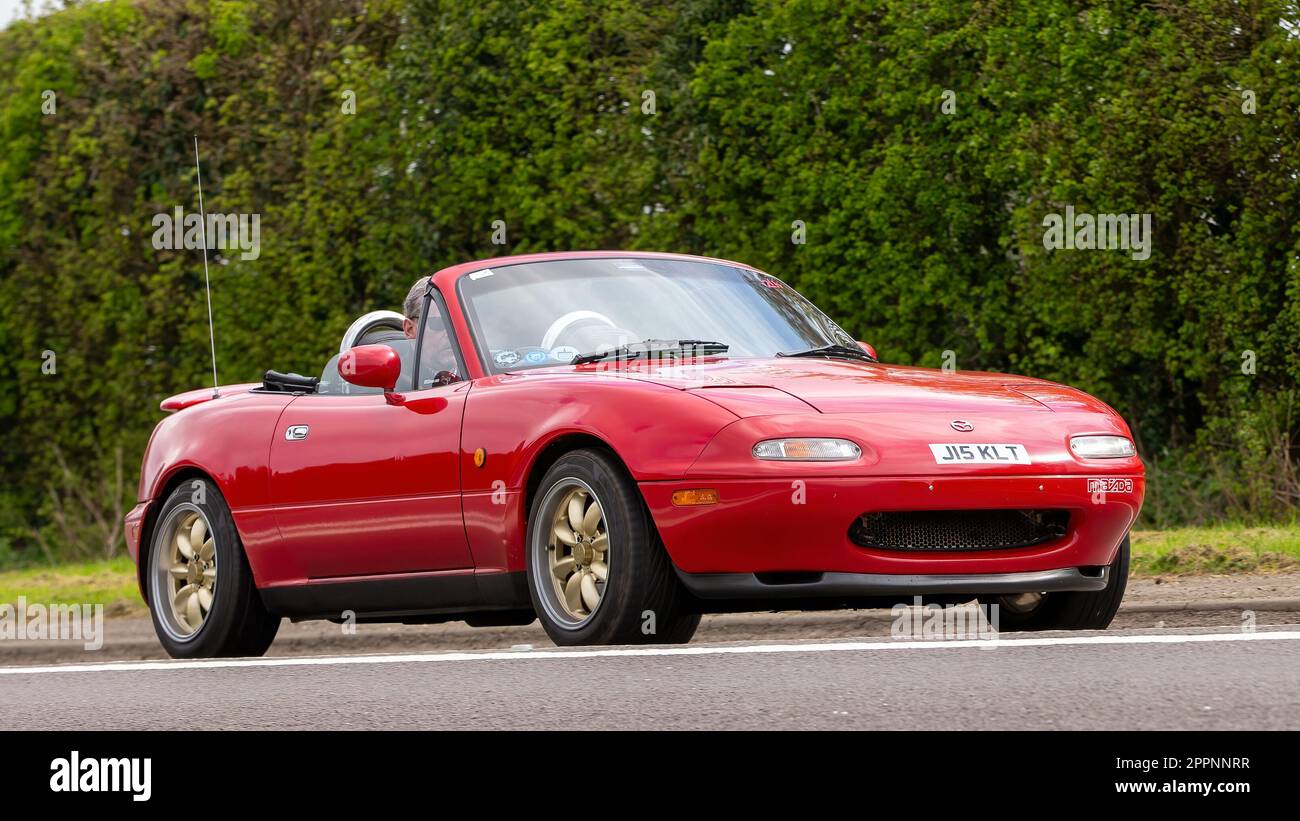 Bicester,Oxon,UK - April 23rd 2023. 1991 red Mazda MX 5 classic  car travelling on an English country road Stock Photo