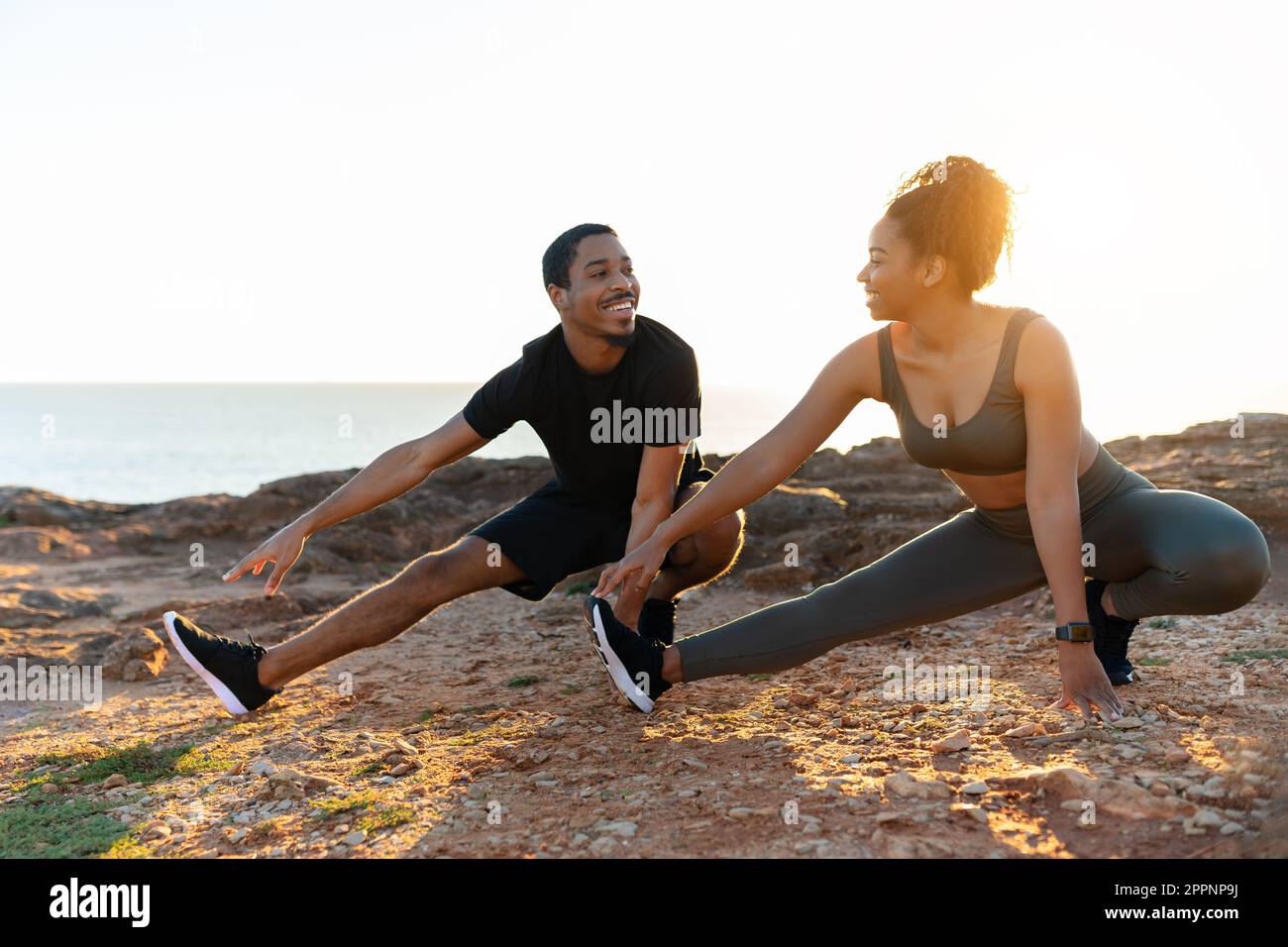 Glad millennial african american couple in sportswear practice yoga, doing  stretching for legs on ocean beach Stock Photo - Alamy