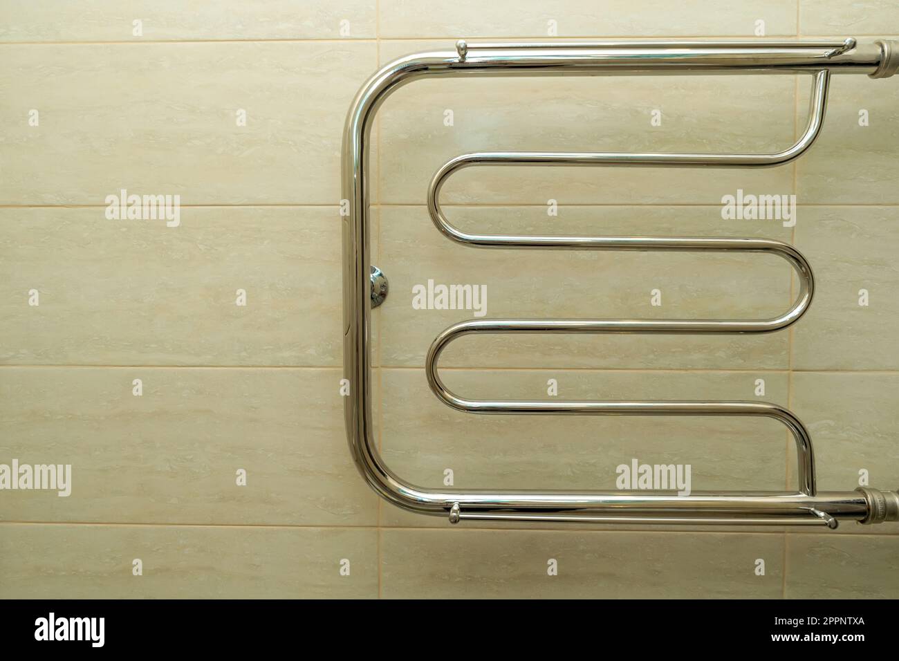 heated towel rail in the bathroom on the background of beige ceramic