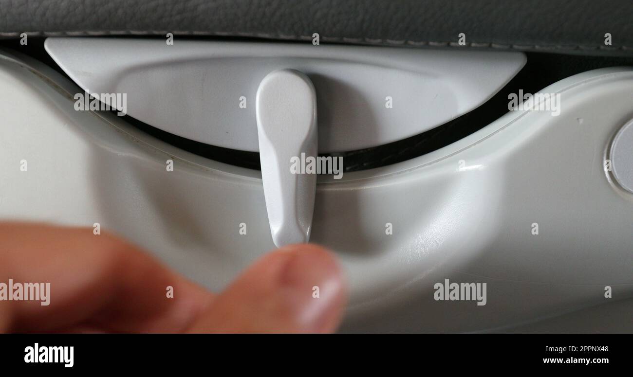 Airplane tray table lock. Closeup of passenger hand opening and closing