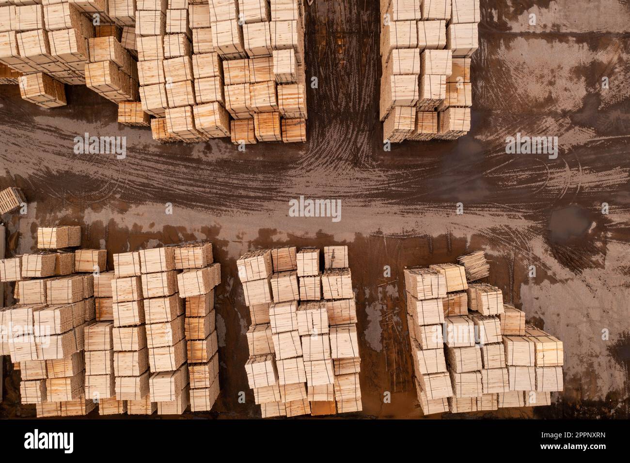 Drone footage piles of lumber in sawmill during summer day. Directly