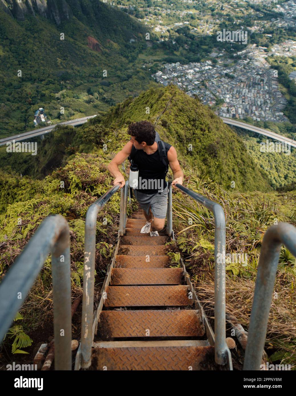 Man Hiking Stairway to Heaven (Haiku Stairs) on Oahu, Hawaii. High quality photo. Looking up the stairs. Stock Photo