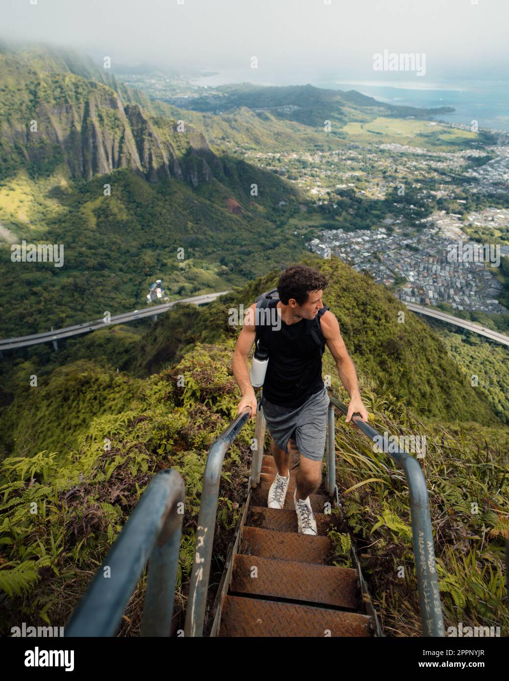 Man Hiking Stairway to Heaven (Haiku Stairs) on Oahu, Hawaii. High quality photo. Looking up the stairs. Stock Photo