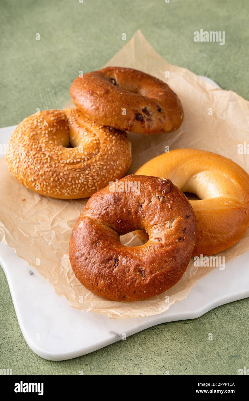 Homemade freshly baked bagels on a parchment paper ready to eat, cinnamon raisin, sesame and plain bagel Stock Photo