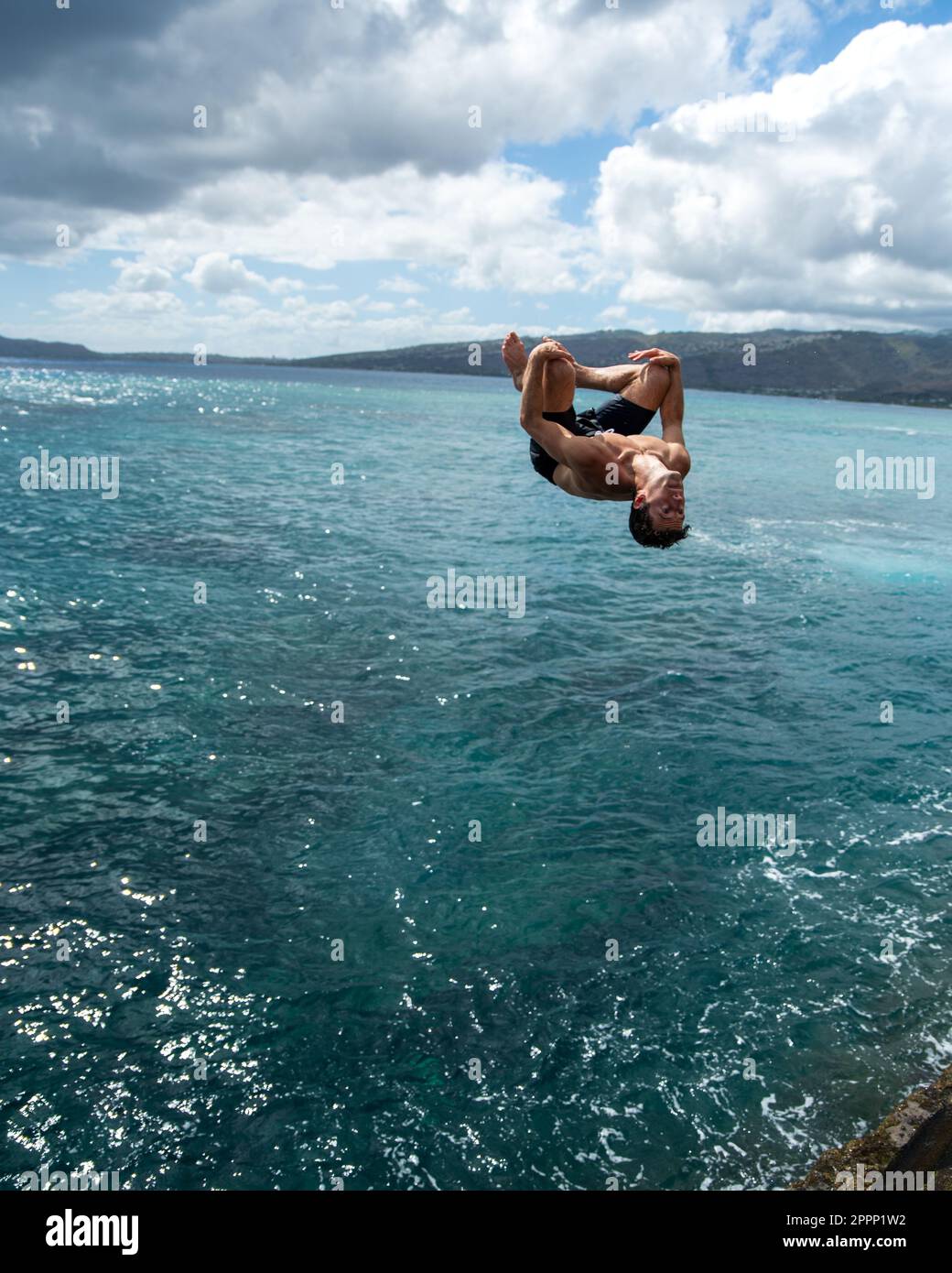 Man cliff jumping off Spitting Cave on Oahu, Hawaii. High quality photo