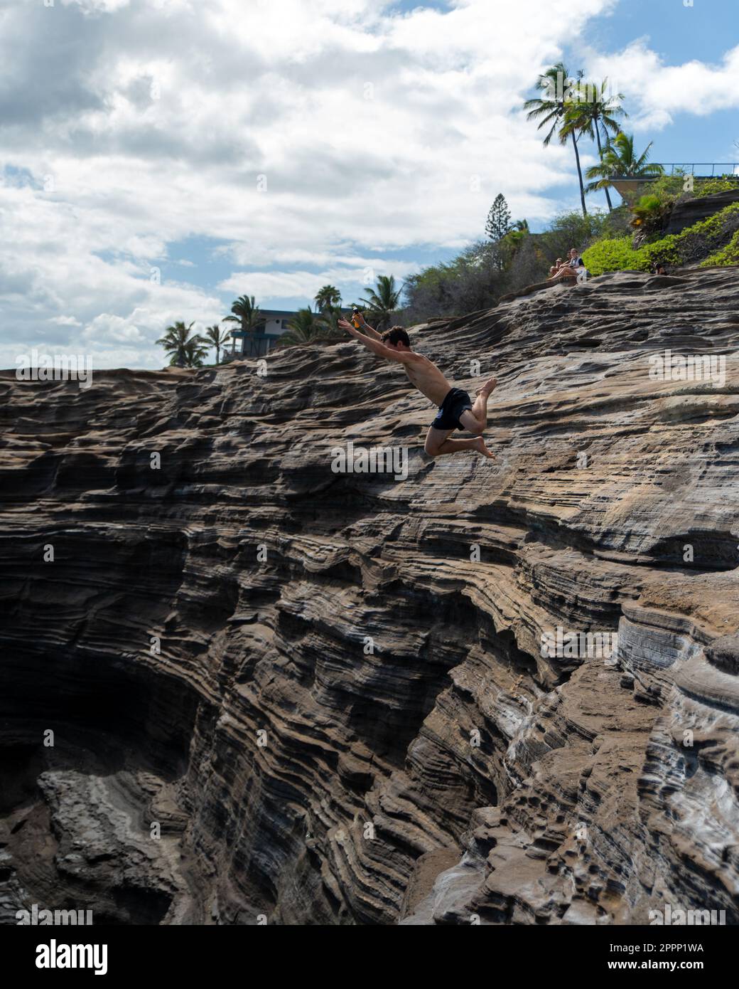 Man cliff jumping off Spitting Cave on Oahu, Hawaii. High quality photo