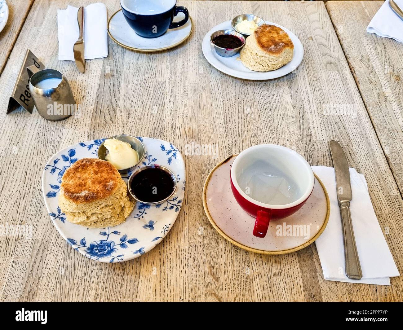 Cream tea served on a table scone with marmalade and cream. Tea cups