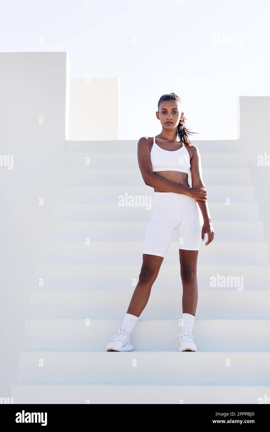 https://c8.alamy.com/comp/2PPPBJD/full-length-slim-fit-female-in-white-sports-attire-woman-standing-on-white-stairs-relaxing-during-training-2PPPBJD.jpg