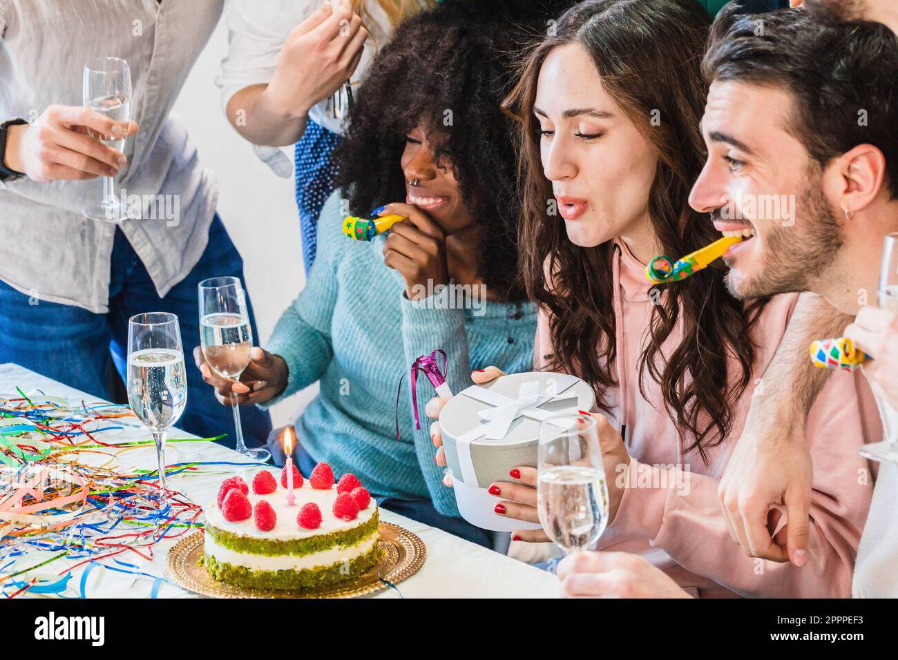 Birthday party with friends. Girl blowing out candles on cake and