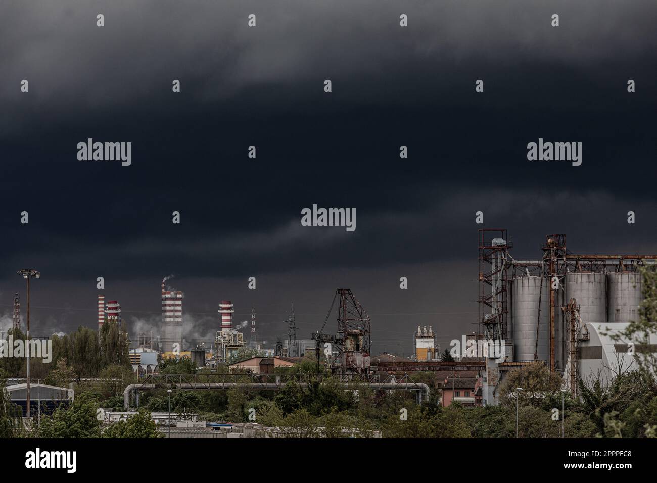 Large gray clouds in a leaden sky before a thunderstorm and urban pollution fumes near factories in the industrial area Stock Photo