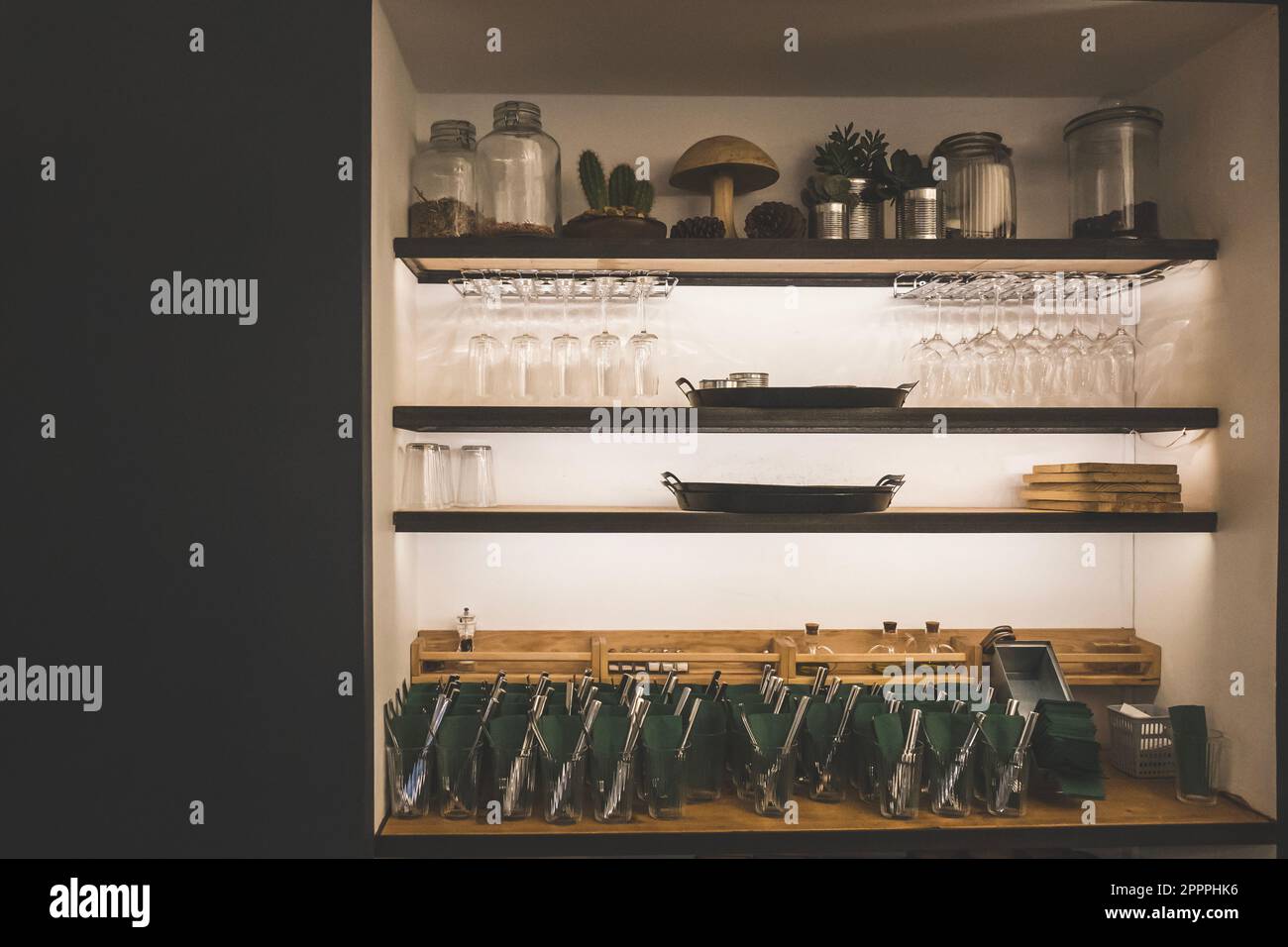 Set of utensils, glass wines and containers arranged on a wall wooden shelves in cafe or restaurant Stock Photo