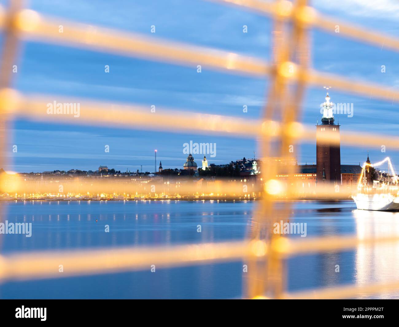 Stockholm, Sweden - 4 October, 2022: A blurred fence in front of a majestic city hall with a stunning motif stands tall, reflecting off the still wate Stock Photo