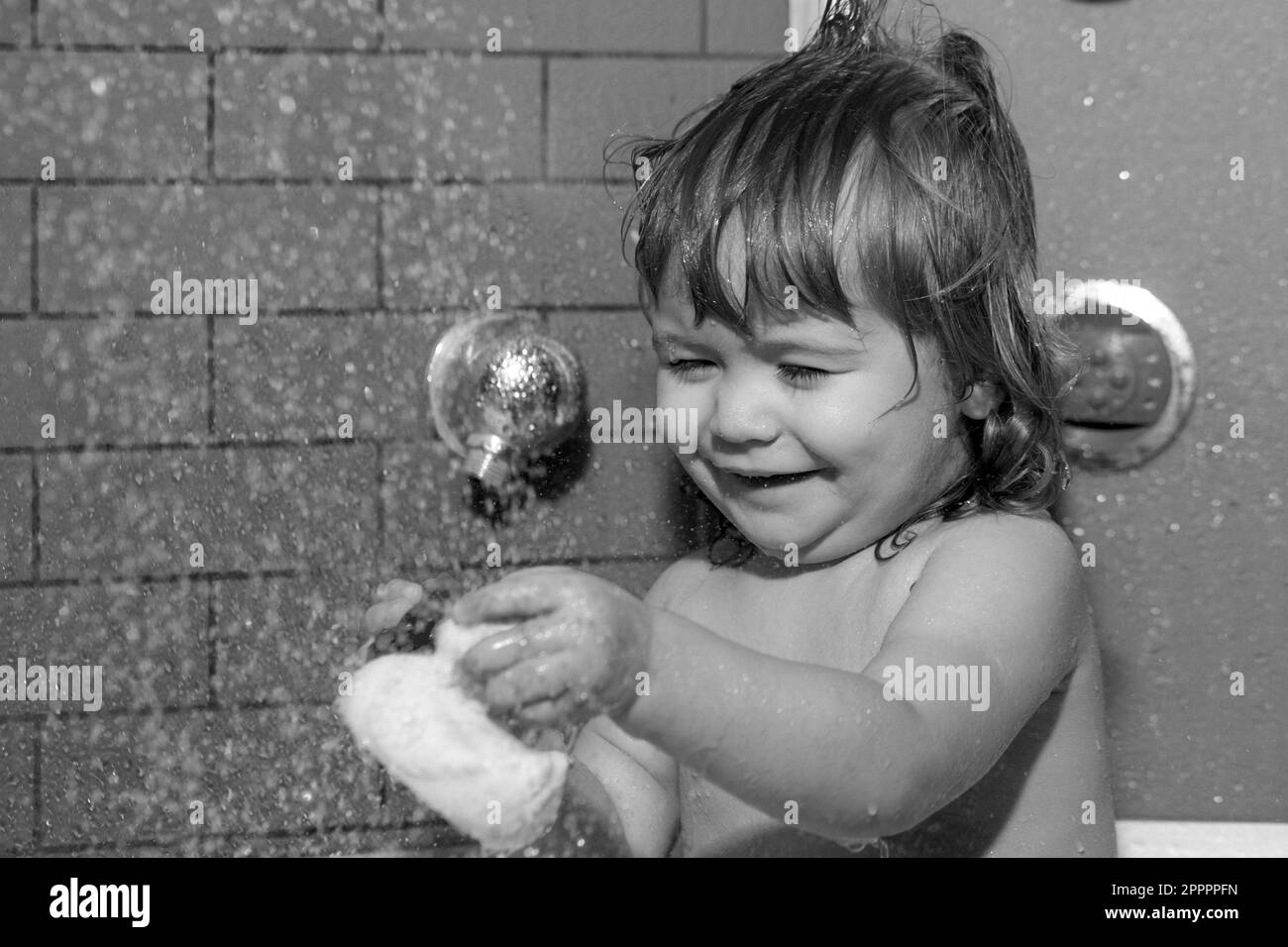 Child bathes in a shower. Bathing baby. Happy kid with soap foam on