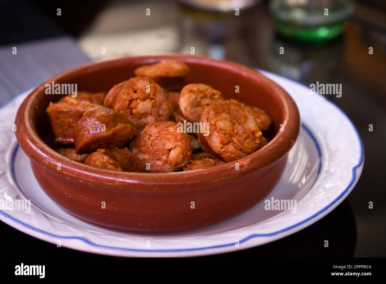 Delicious sausages in cider in a traditional clay bowl on a white plate