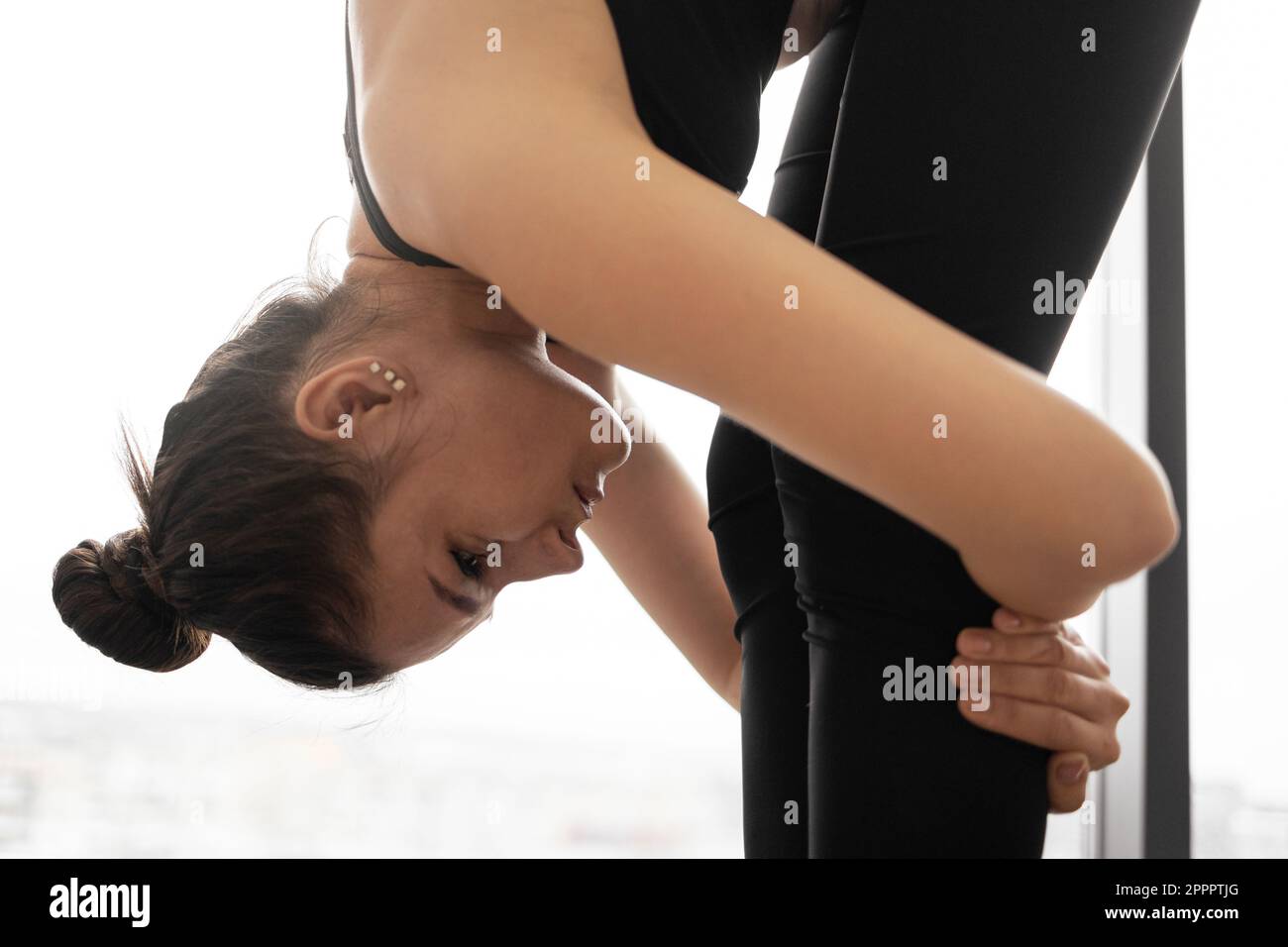 Crop view of slim young woman in black sportswear embracing legs and ...