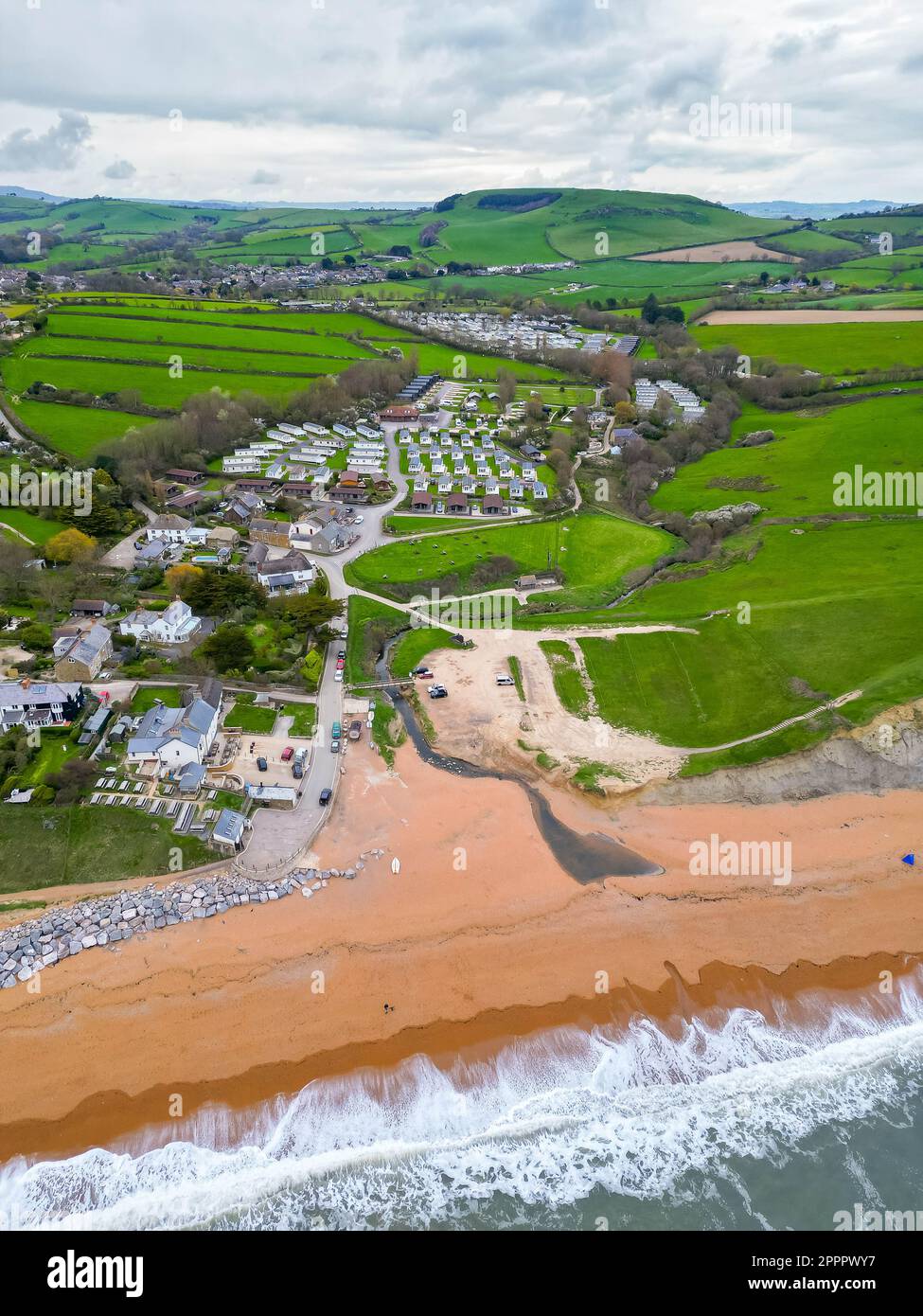 Seatown, Dorset, UK.  24th April 2023.  View from the air of the beach, River Winniford and village at Seatown on the Dorset Jurassic Coast.  In 2022, the sewer storm overflow 500 meters inland next to the River Winniford at the Chideock sewage treatment works owned by Wessex Water, (Permit number: 401068) spilled 35 times for a total of 363.50 hours, discharging into the River. (Source: https://theriverstrust.org/key-issues/sewage-in-rivers) Picture Credit: Graham Hunt/Alamy Live News Stock Photo