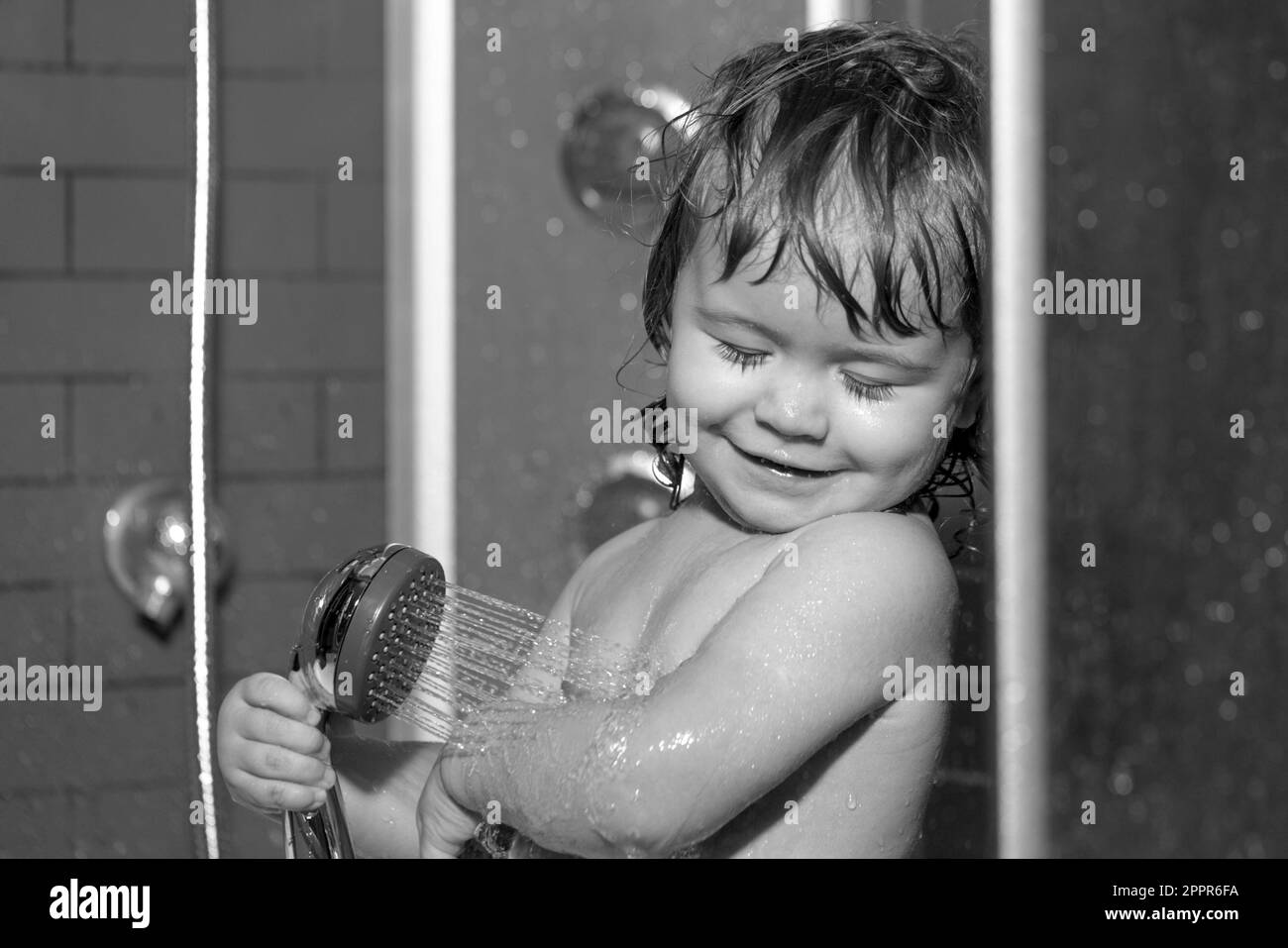 Child having fun to bath. Happy baby taking a bath playing with foam