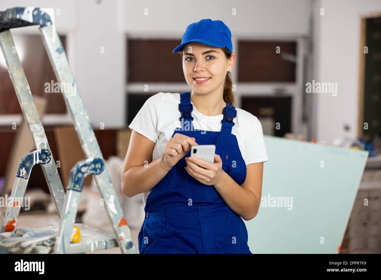 Young woman builder using smartphone in construction site Stock Photo