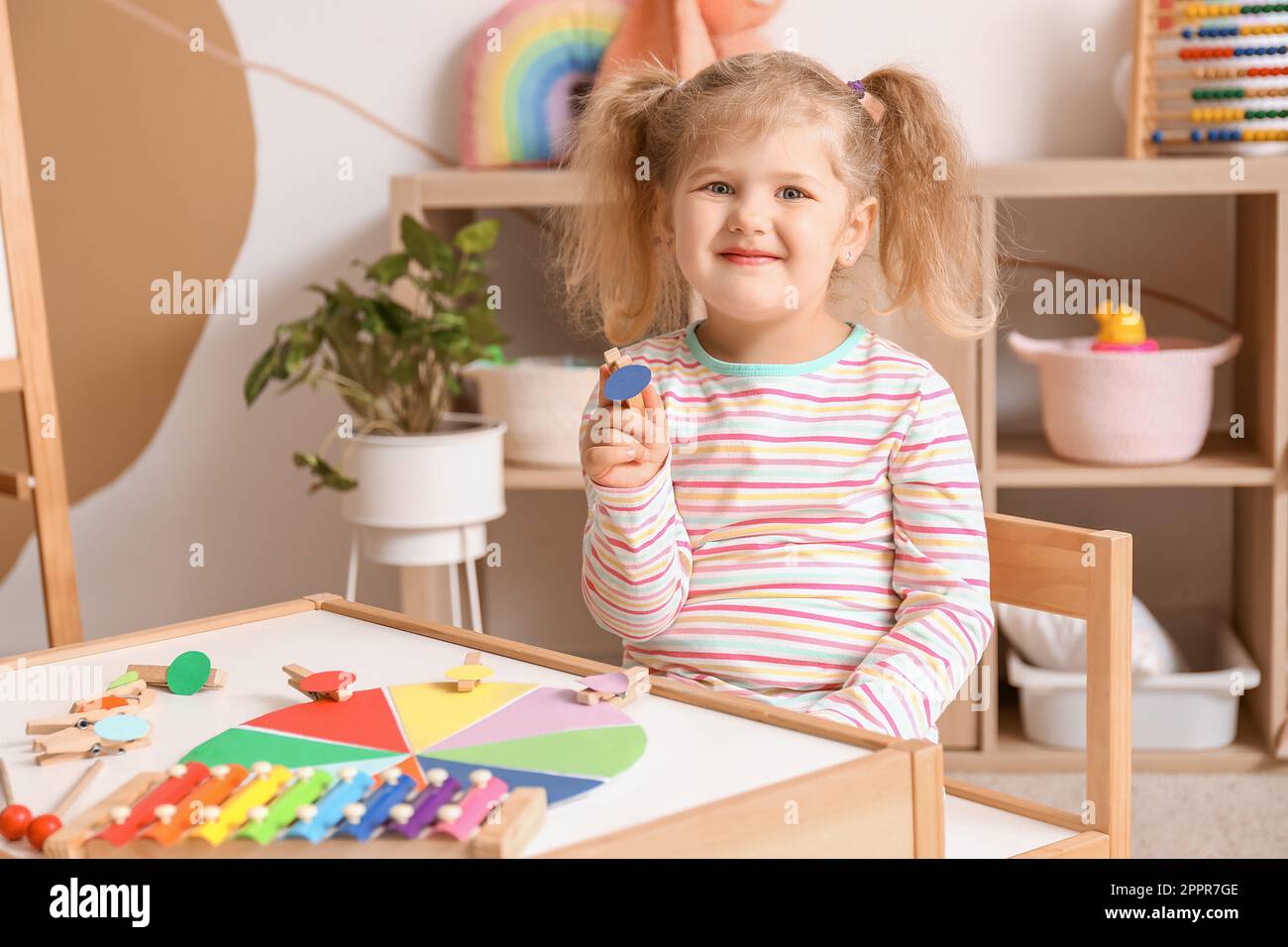 Cute little girl playing matching game with clothespins at home Stock
