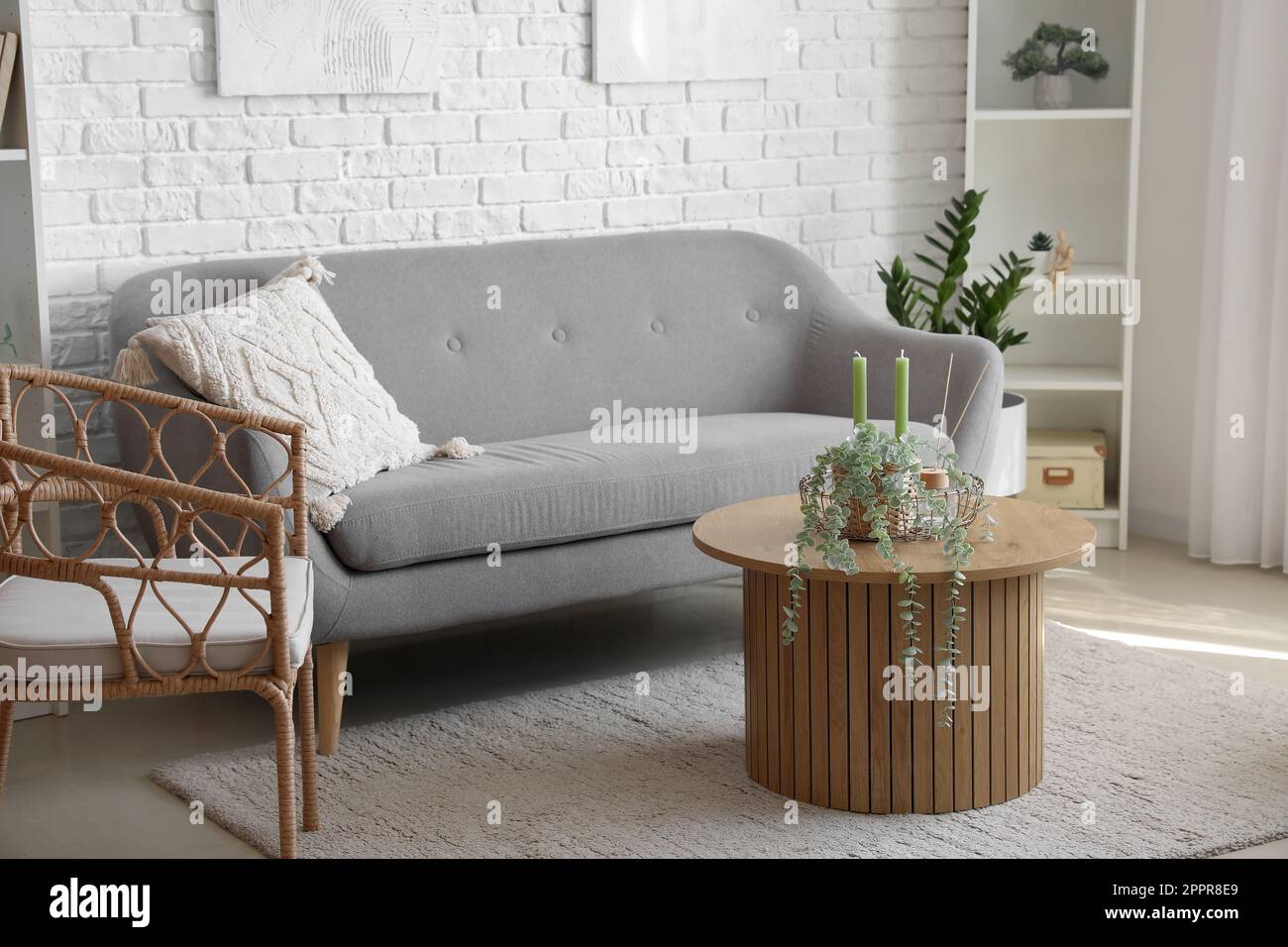 Interior of bright living room with cozy grey sofa, armchair and coffee
