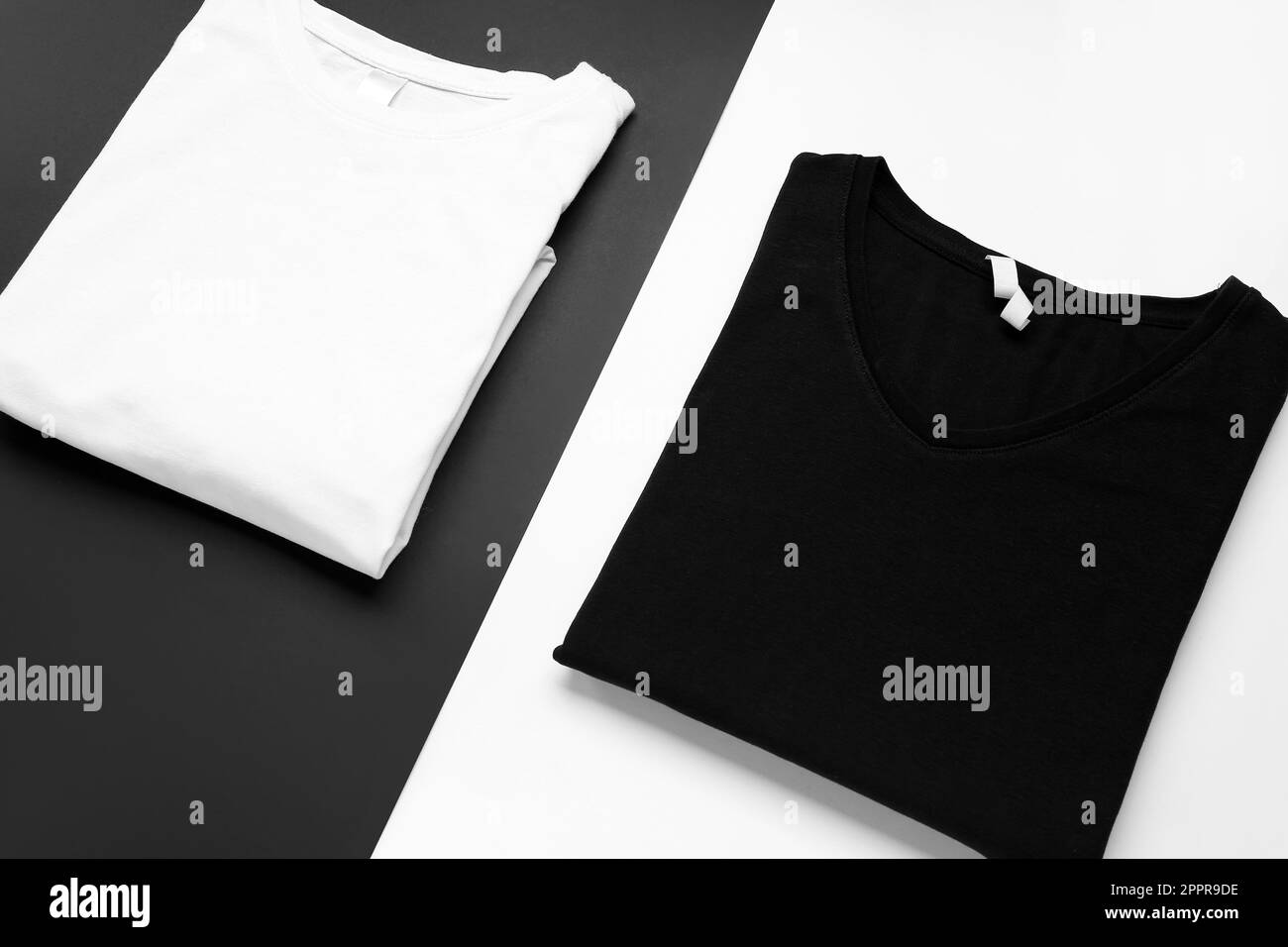 Folded black and white t-shirts on color background Stock Photo - Alamy