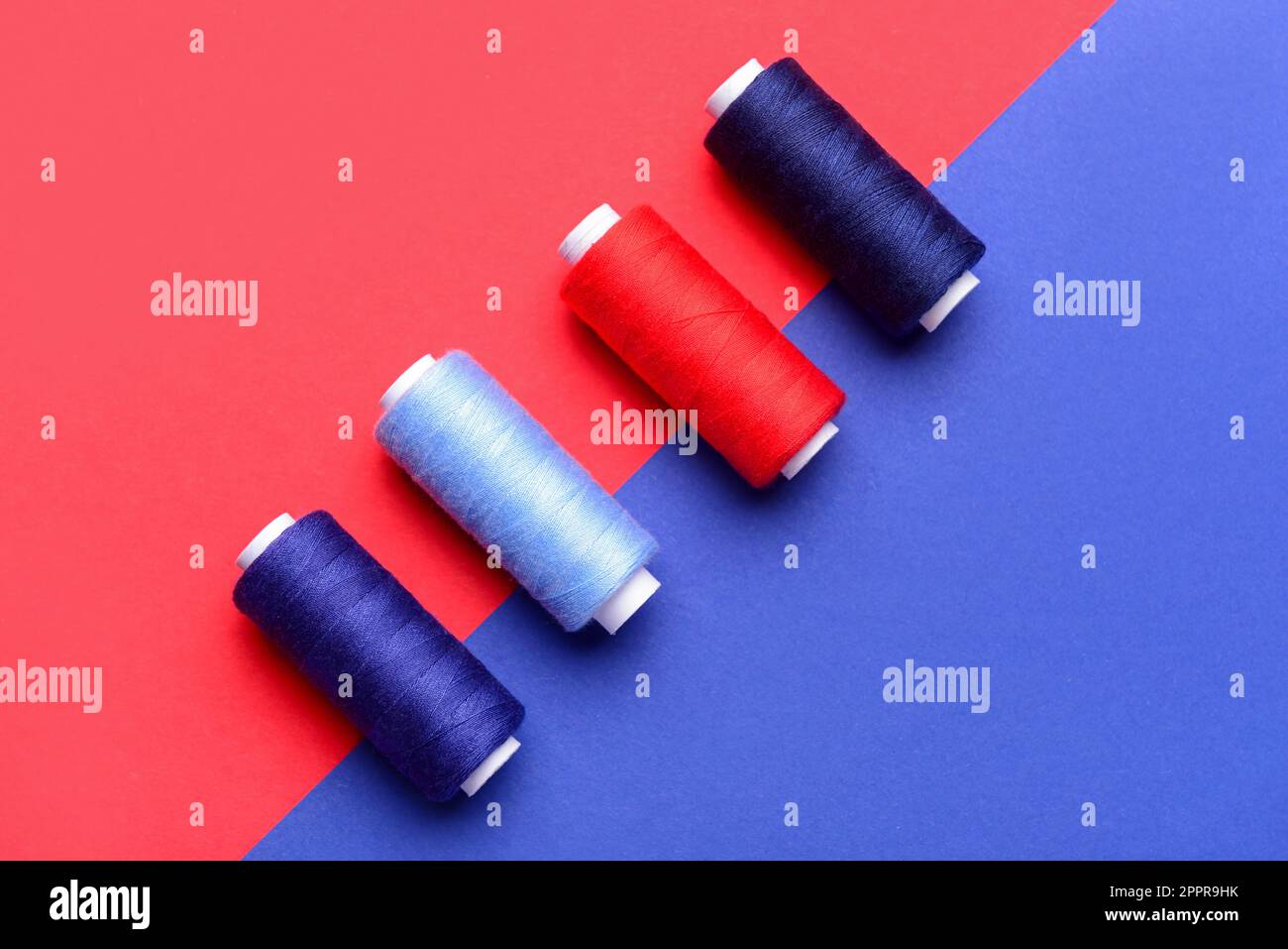 Different sewing threads on color background Stock Photo - Alamy