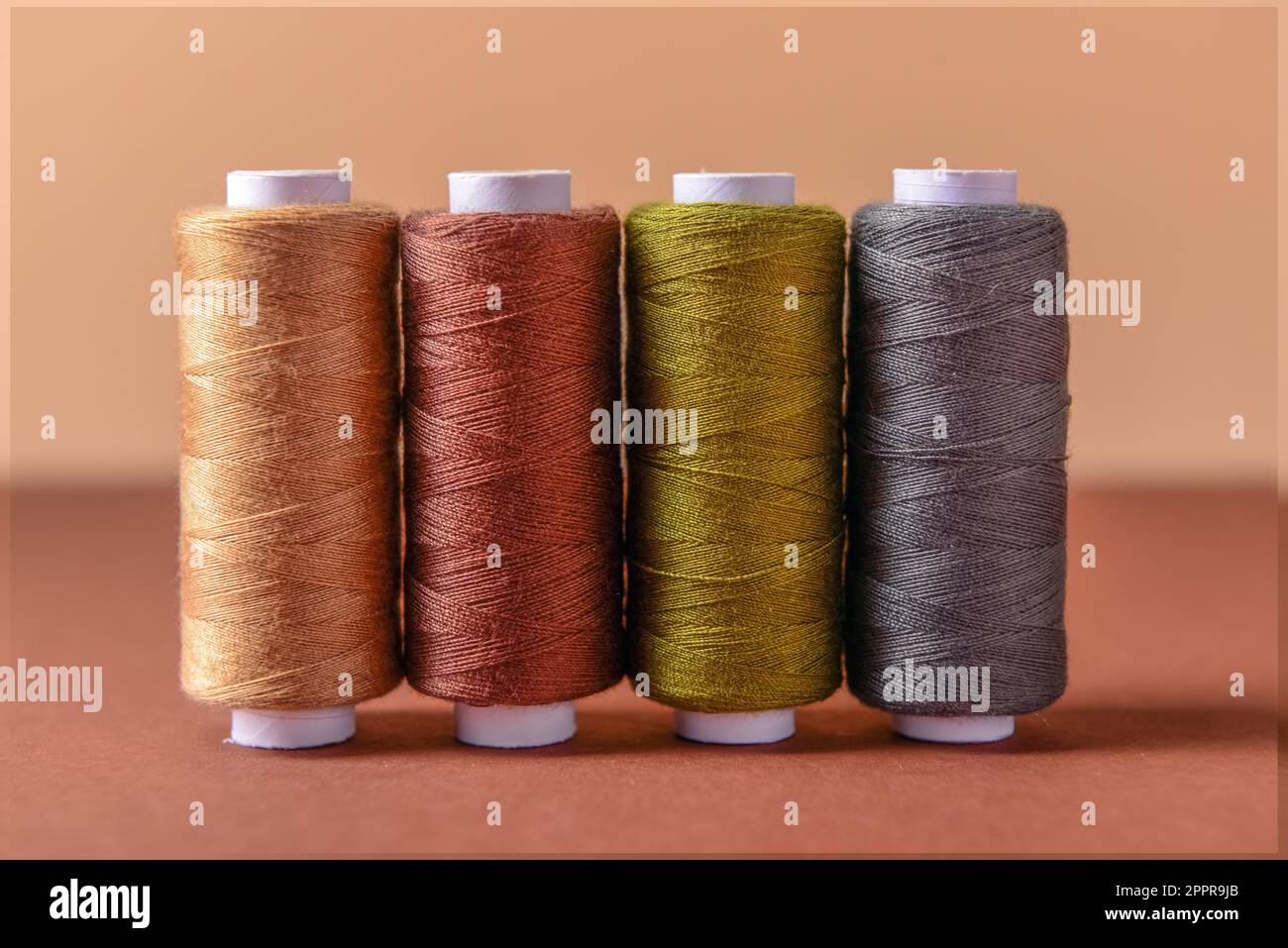 Row of thread spools on color background Stock Photo - Alamy