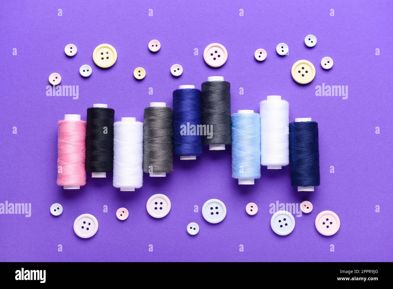 Composition with different thread spools and buttons on color background Stock Photo