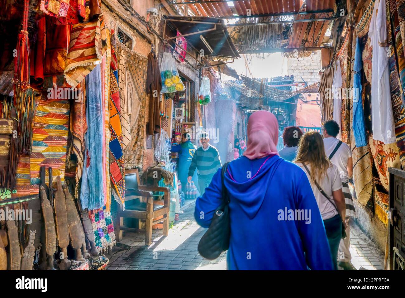 Marrakech, Morocco - Oct 19, 2015. Early morning in the Old City souk, as pedestrians walk on a narrow street past shops selling tourist merchandise. Stock Photo