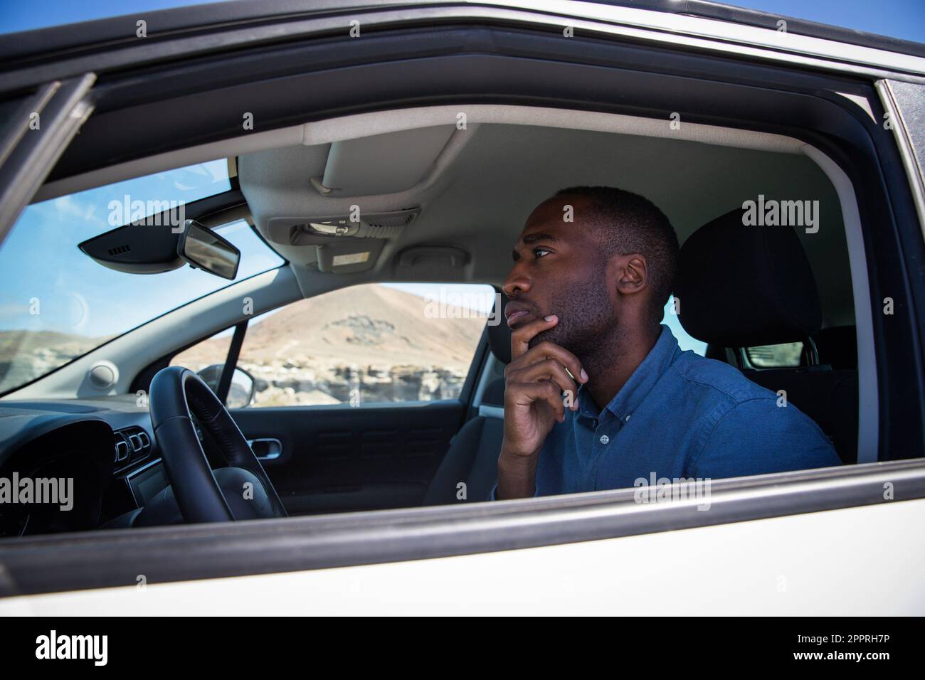 An African American man with a thoughtful expression sitting in his car Stock Photo