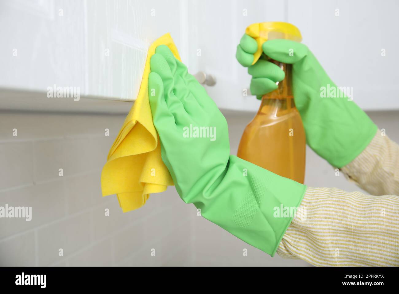 Woman cleaning white cupboard with rag and detergent indoors, closeup Stock Photo
