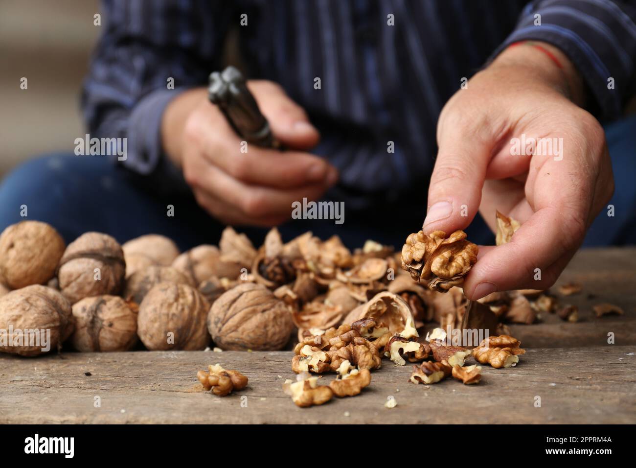 Man cracking walnuts at wooden table, closeup Stock Photo