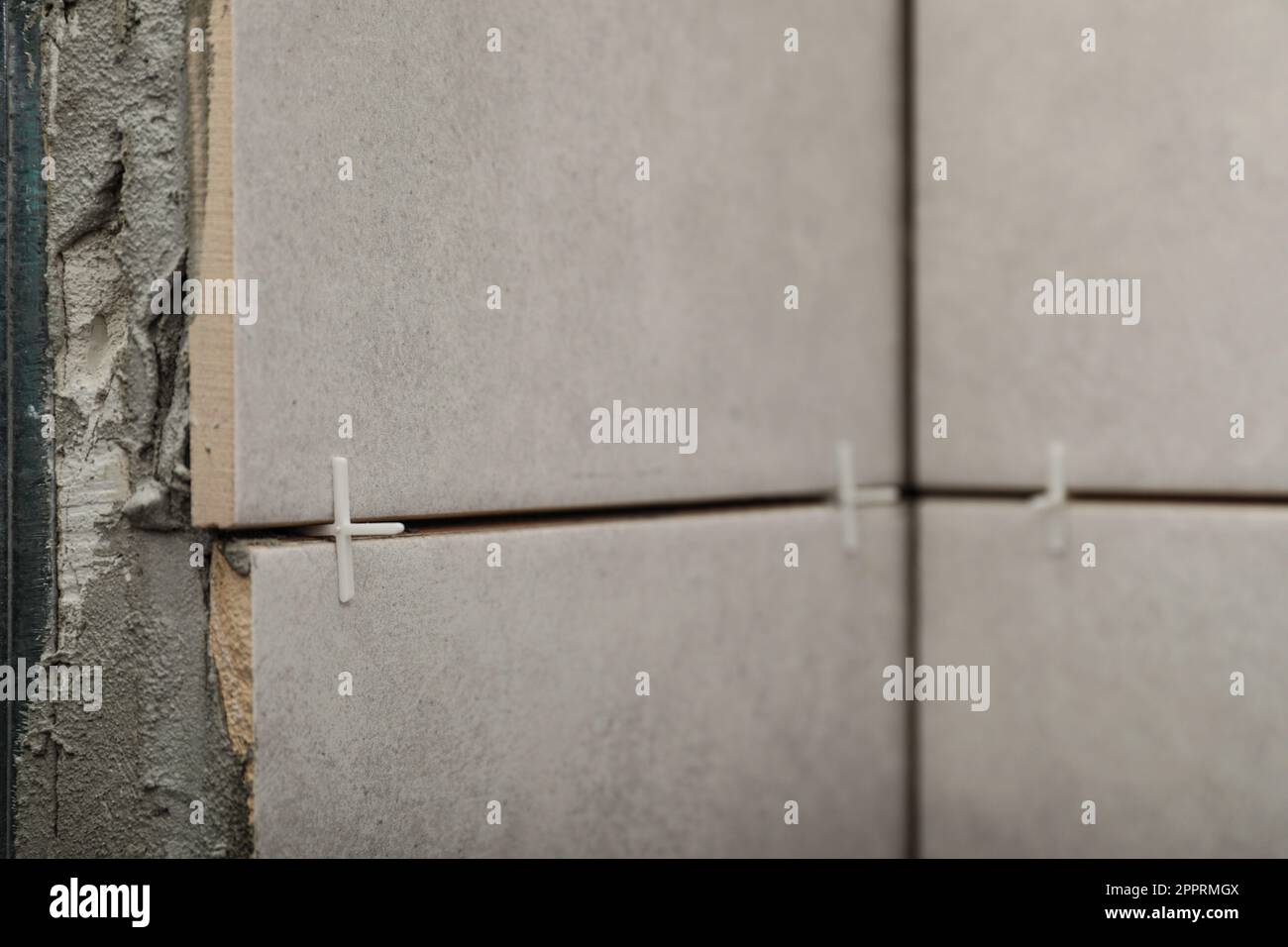 Stylish tiles with spacers on wall in room Stock Photo Alamy