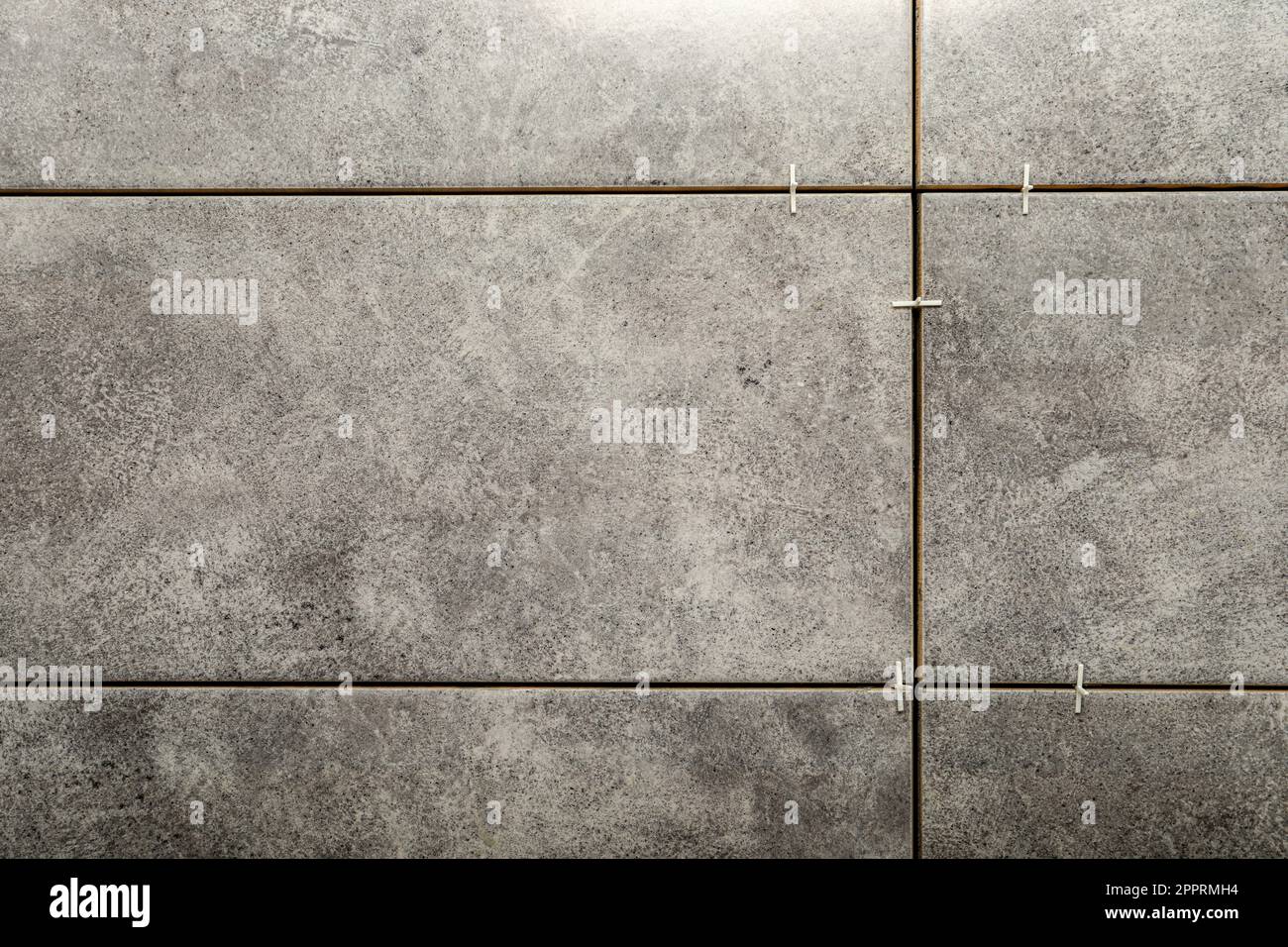 Stylish tiles with spacers on wall in room Stock Photo Alamy