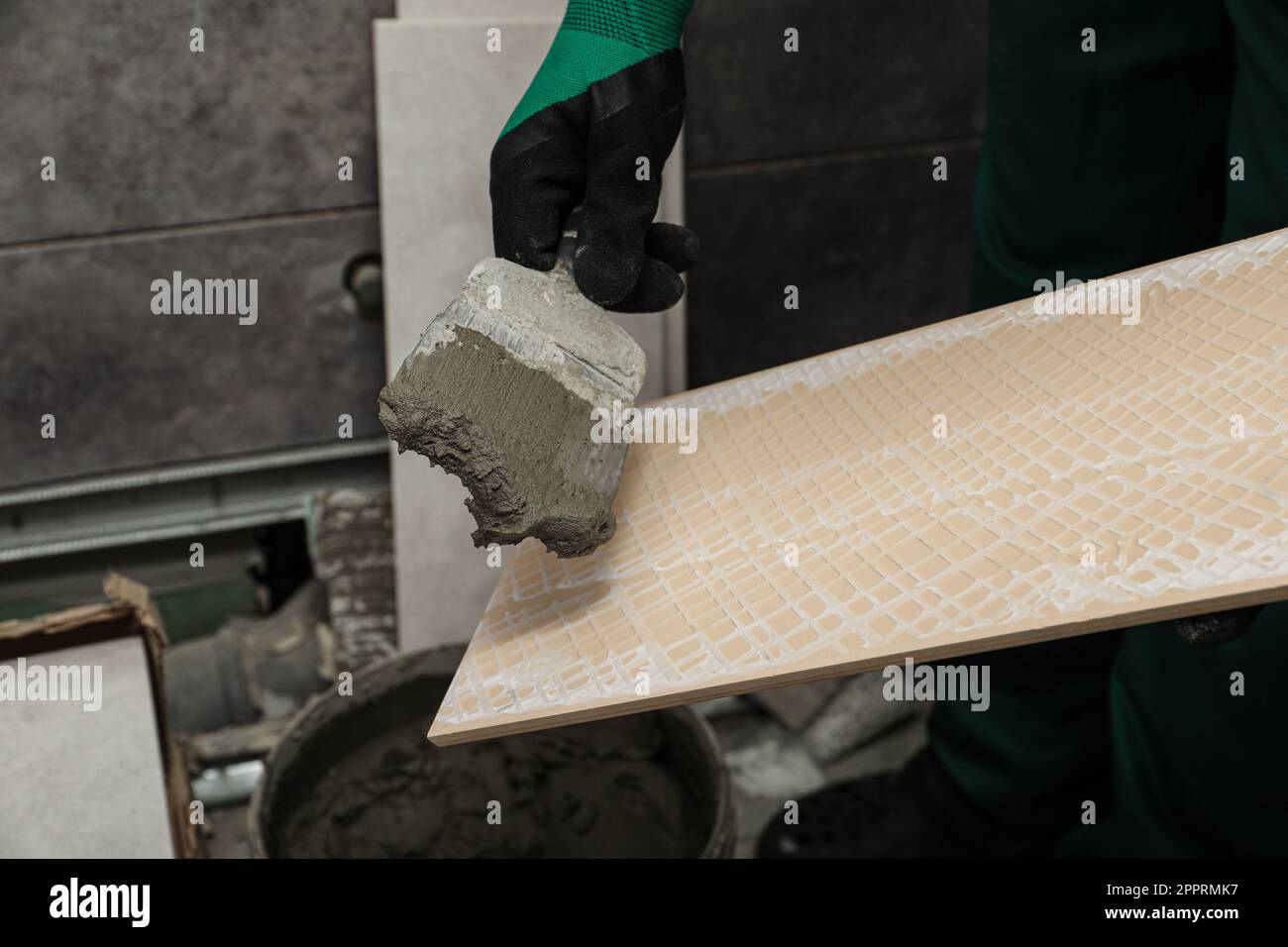 Worker applying adhesive mix on ceramic tile with spatula, closeup ...