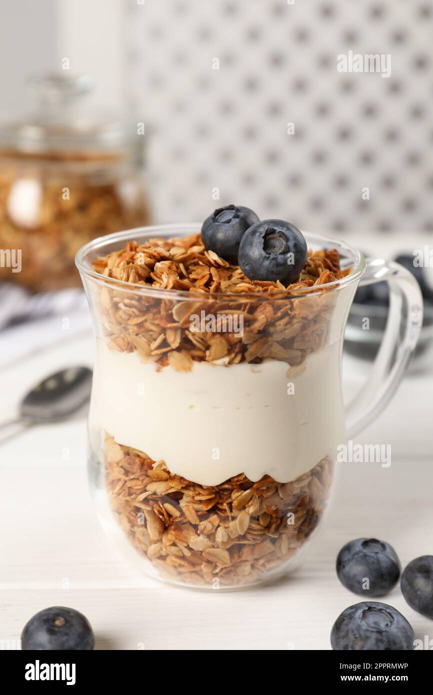 Tasty yogurt with muesli and blueberries in cup served on white wooden table Stock Photo