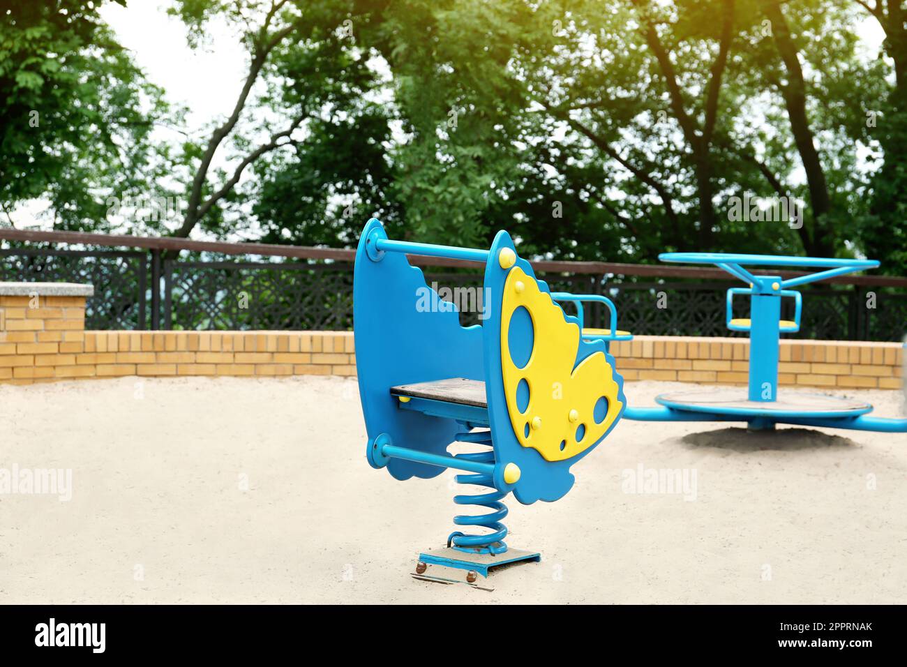 Children's playground with bright butterfly shaped spring rider and roundabout Stock Photo