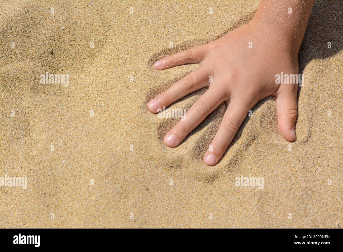 Child leaving handprint on sand outdoors, closeup with space for text