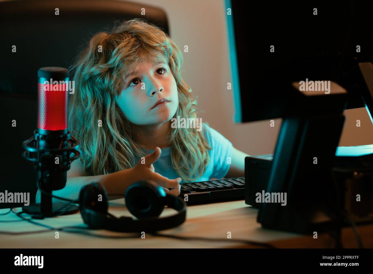 Child with pc computer at night. A pretty child learns a lesson using a ...